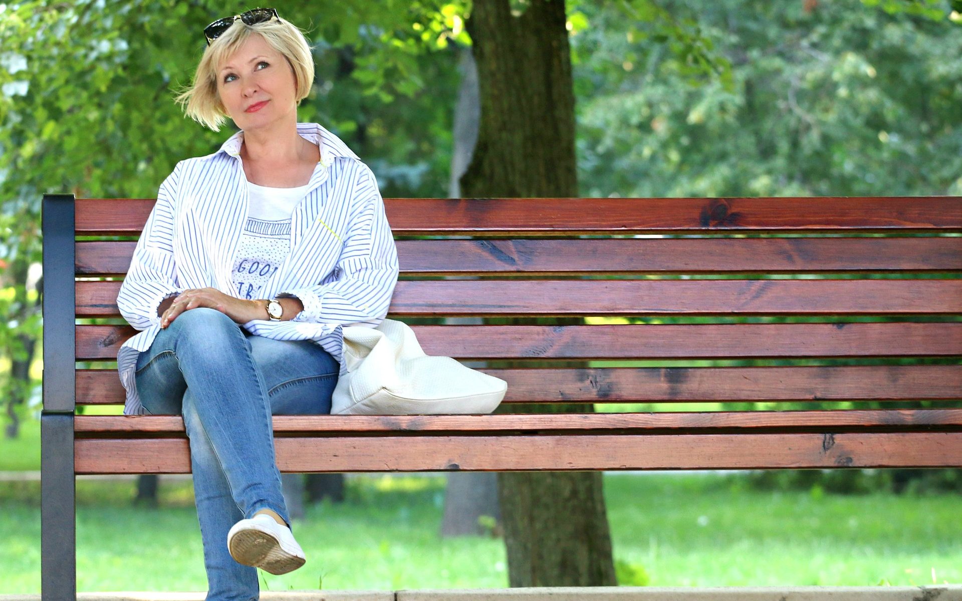 Frau mittleren alters, sittz alleine auf einer Parkbank