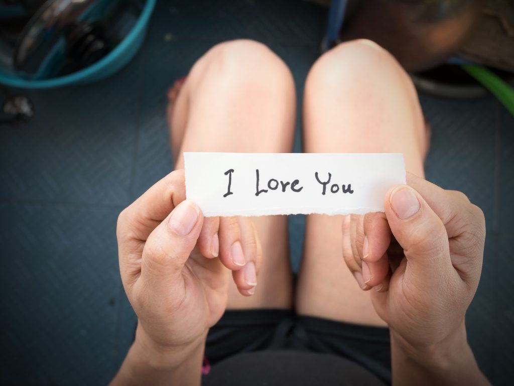 Frau hält Zettel mit "I love You" in der hand