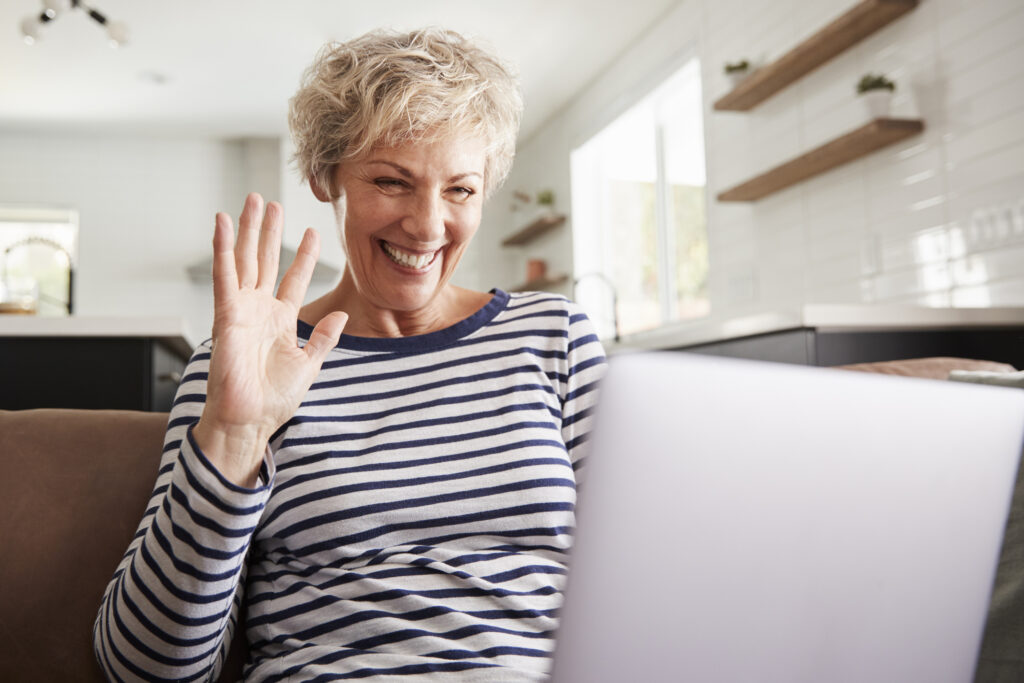 Frau winkt fröhlich im Video-Call