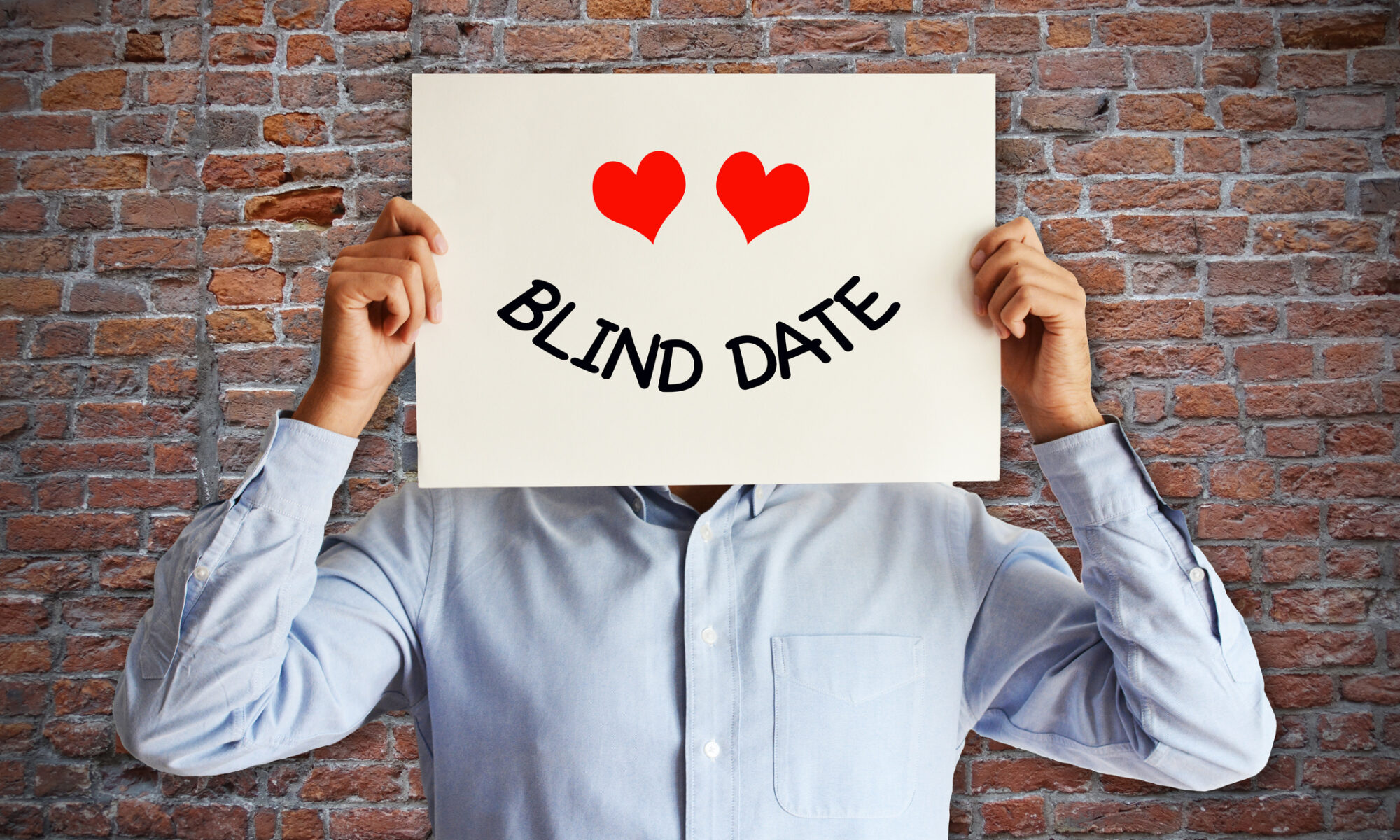 Mann hält sich ein Blind Date Schild vor dem Kopf